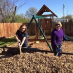 Dori Shirley and Sherry McCarthy shovel mulch.